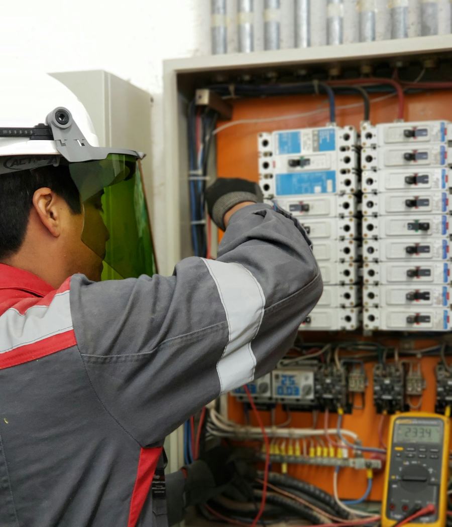 Técnico com EPI fazendo medições em um painel elétrico